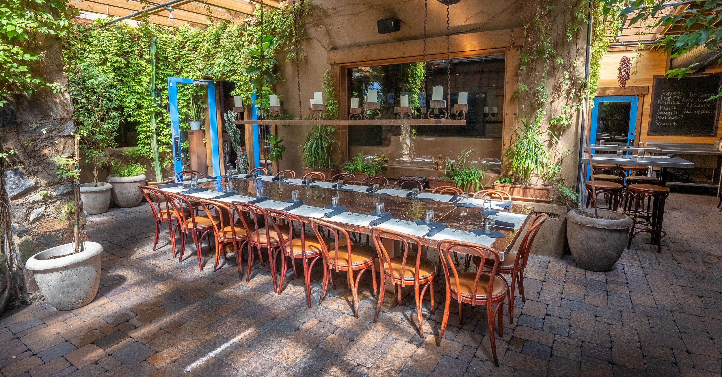 Copper tables, greenery and turquoise doors on Richardson’s covered patio