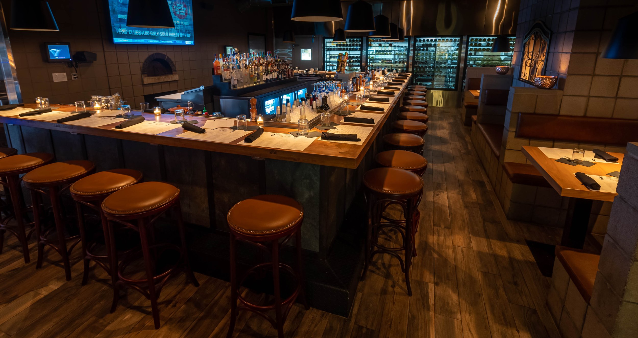 Rosie’s bar with leather stools and warm pendant lighting